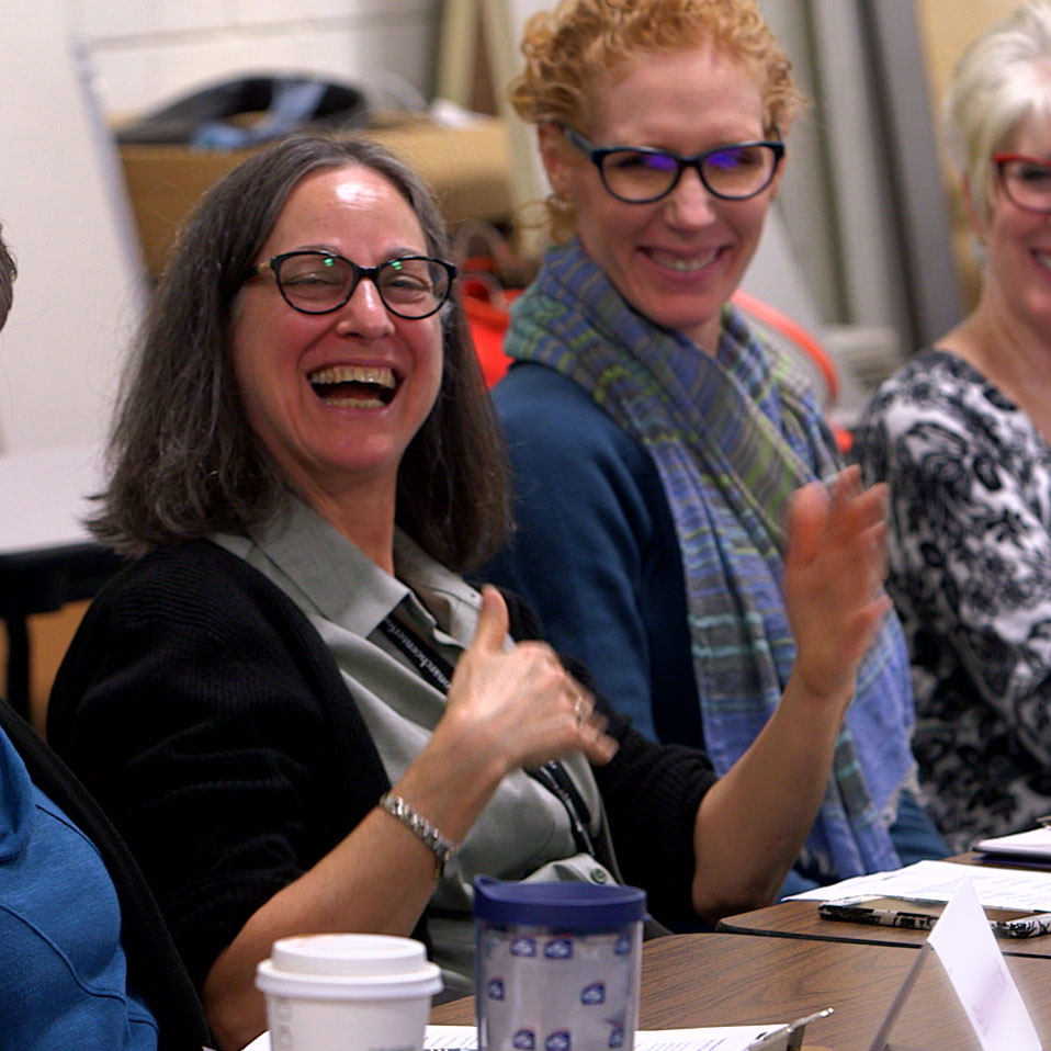 Three women smiling at a table.