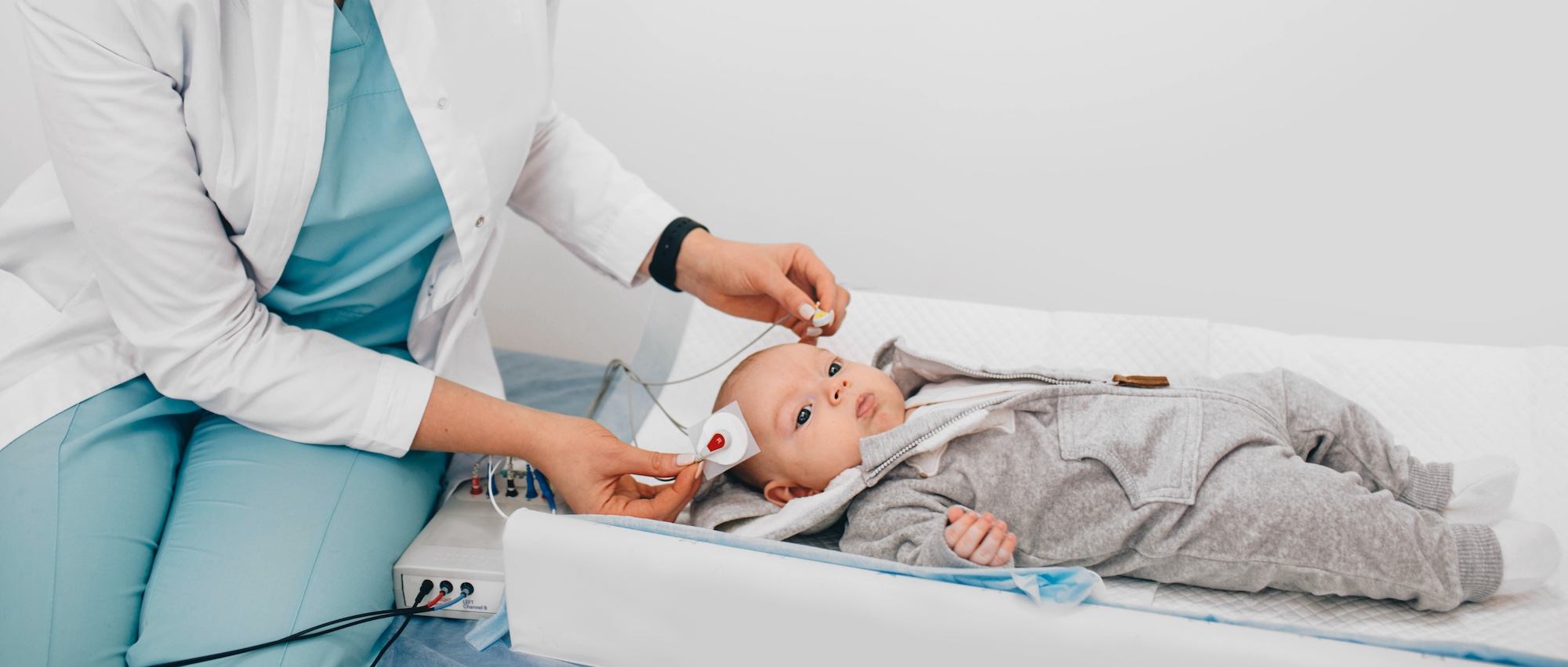 Baby laying on an exam table with doctor preparing for hearing screening