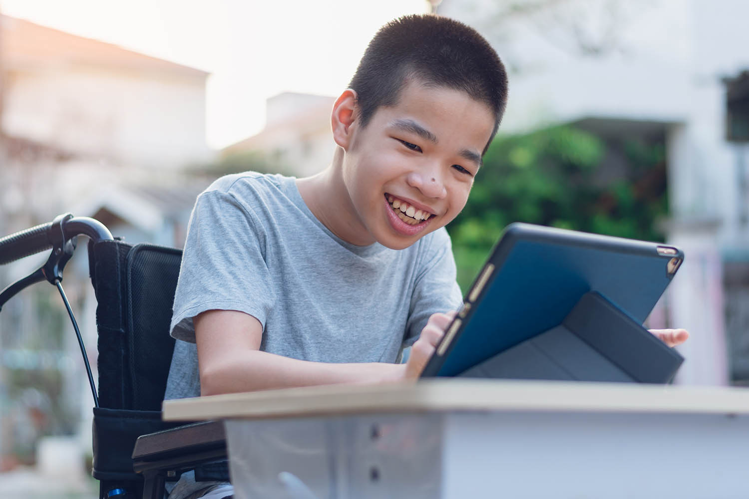 Student sitting at a desk in a wheelchair working on a tablet.