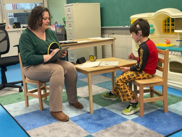 An audiologist administering the Functional Listening Evaluation to a student wearing a cochlear implant.