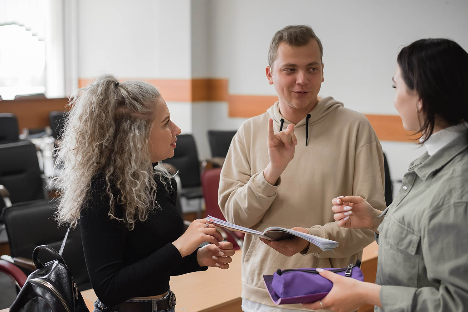 Three deaf adults in a classroom signing to each other.