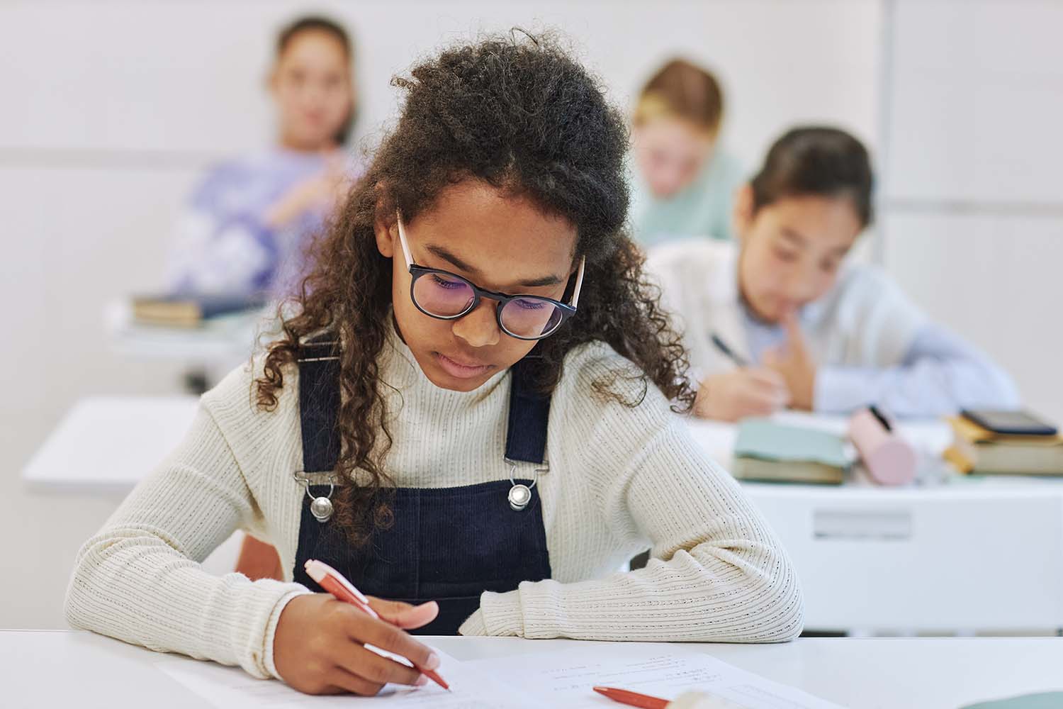 Girl sitting at a desk in a classroom taking an assessment.