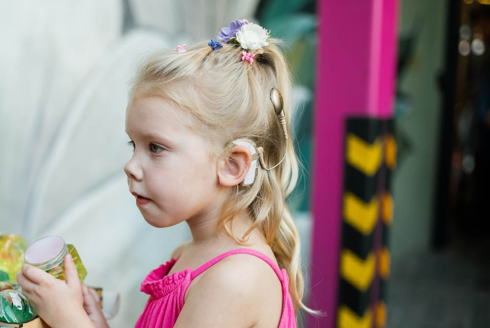 Young girl wearing a cochlear implant holding a toy.