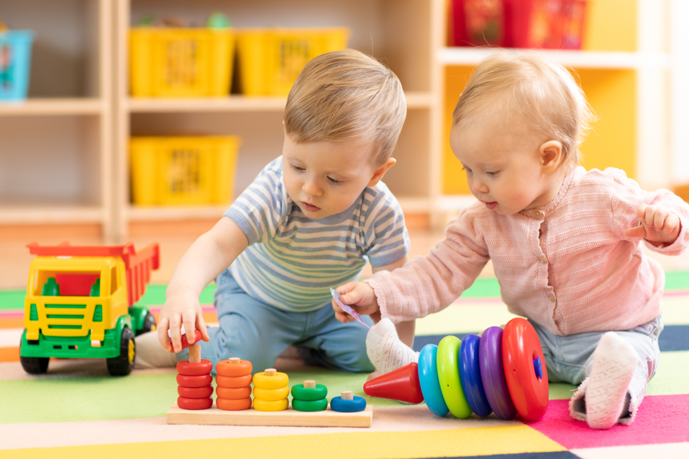 Two children sitting on the floor playing with toys.